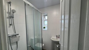 A bathroom with a glass-enclosed shower, a sink, and a toilet. - Apartment Sleeps 7 With Patio (Hayes)