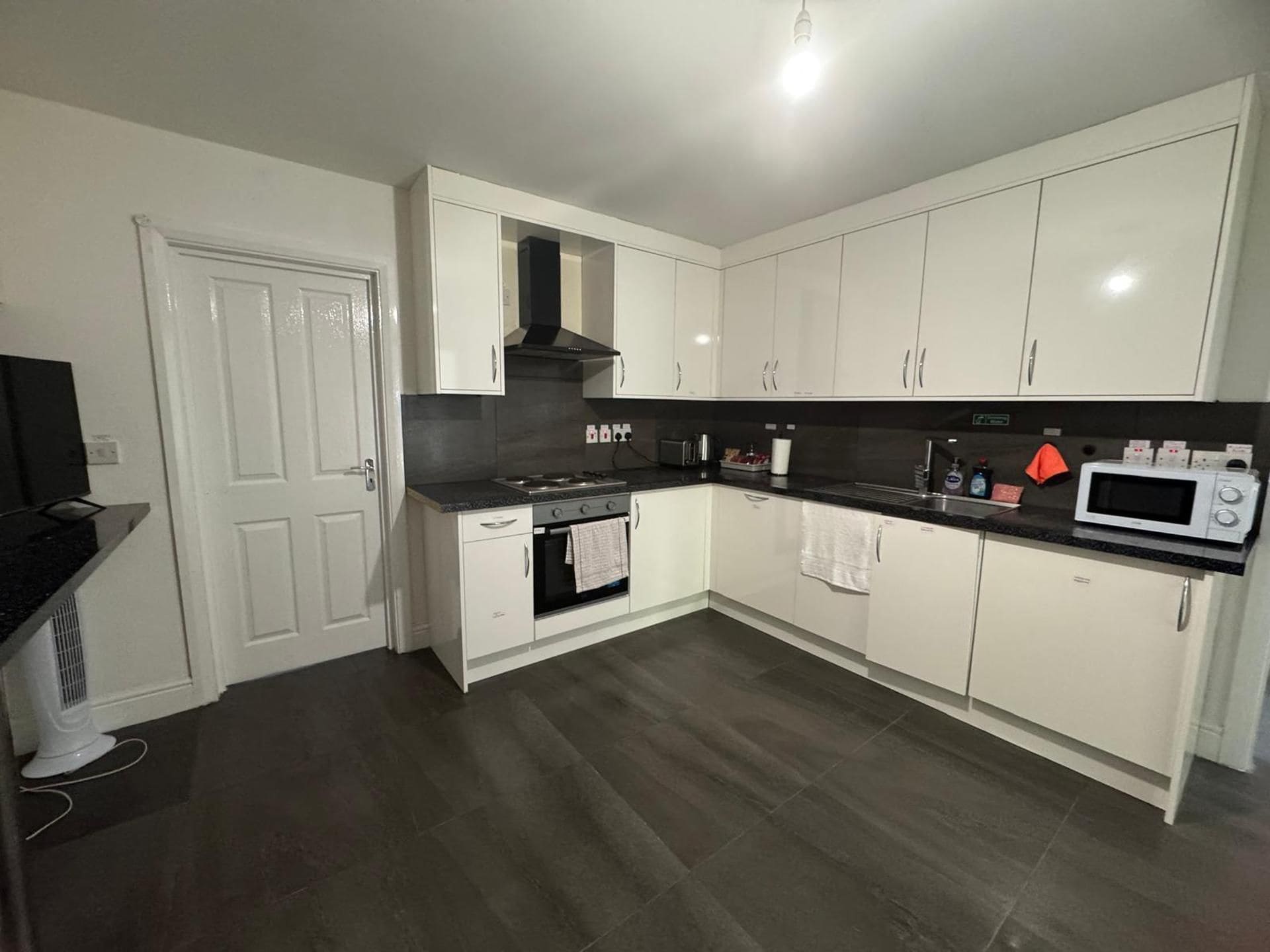 A modern kitchen with white cabinets, a black countertop, and a built-in oven.