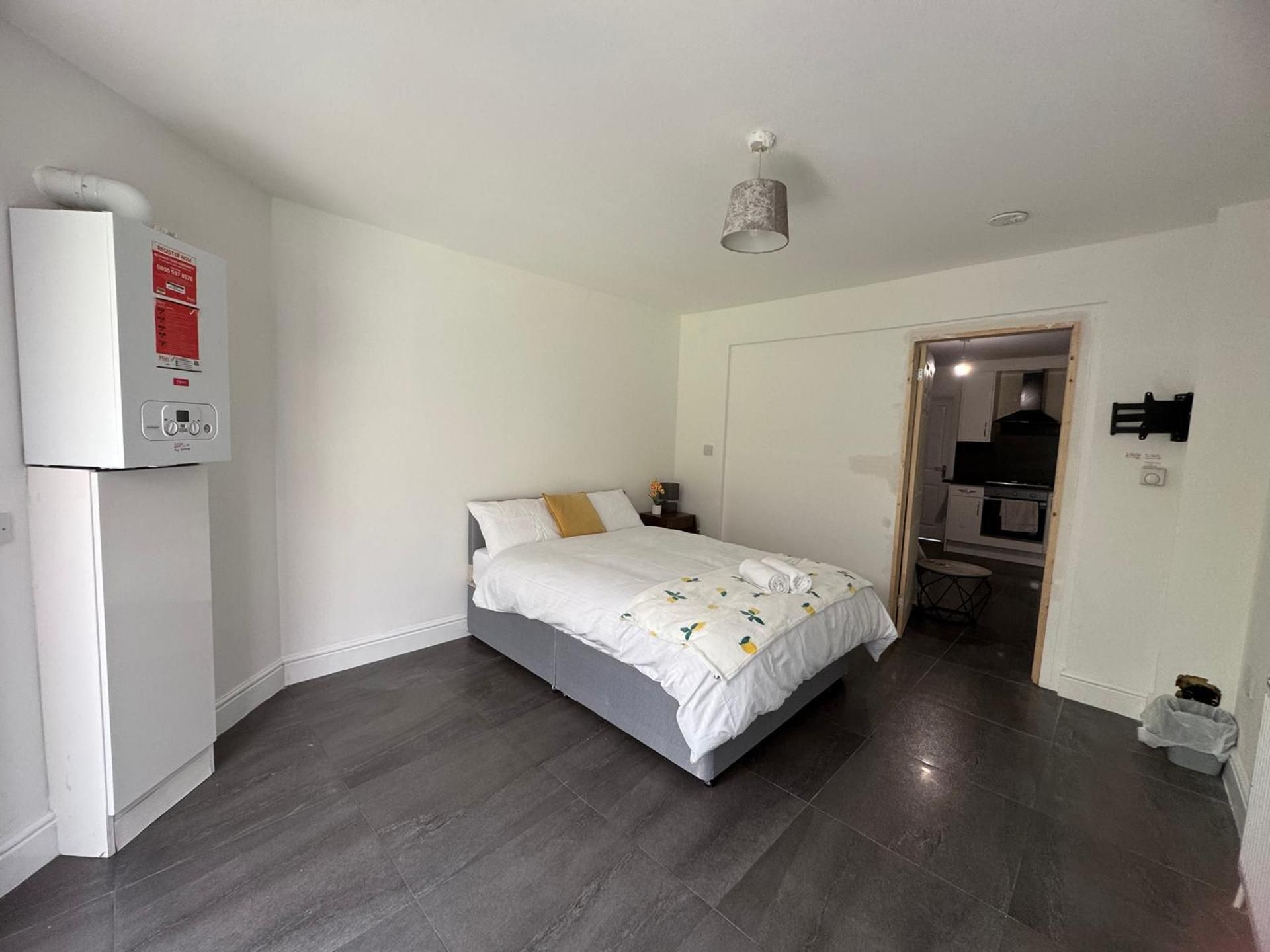 A bedroom with a bed, a heater, and a door leading to a bathroom.