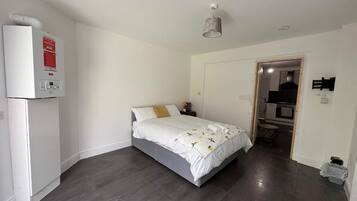 A bedroom with a bed, a heater, and a door leading to a bathroom.