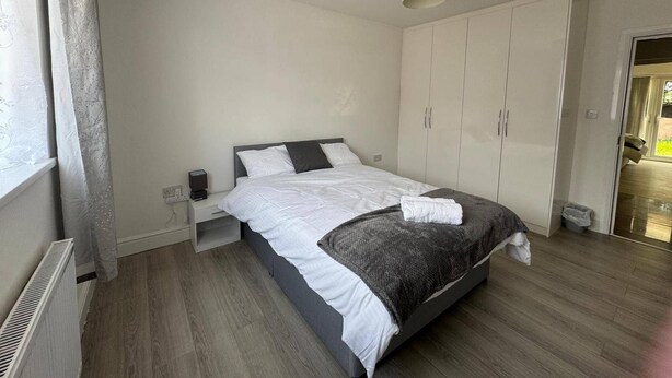 A bedroom with a bed, a bedside table, a wardrobe, and a radiator. - Apartment Sleeps 7 With Patio (Hayes)