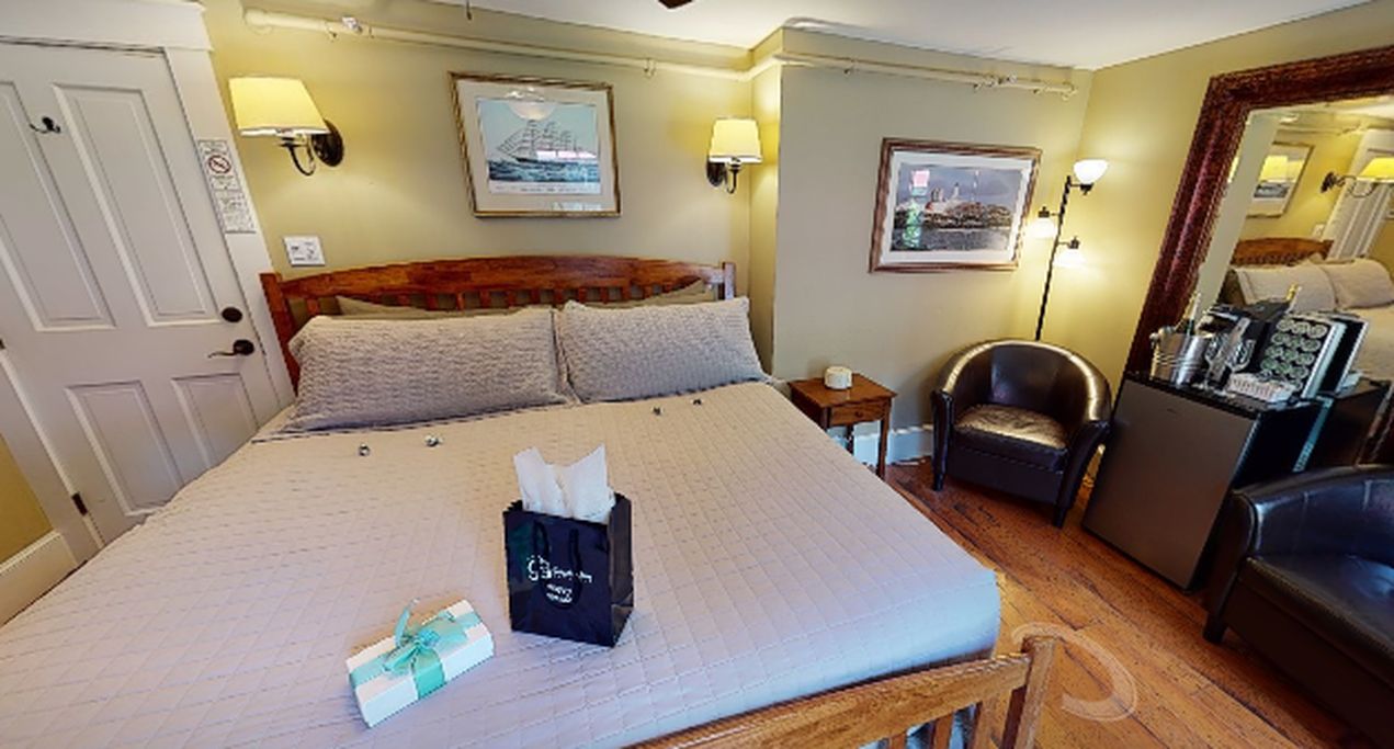 A hotel room with a large bed, bedside lamps, a chair, a desk, and a mirror.