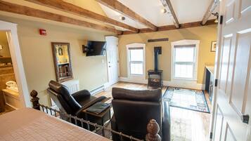 A room with a bed, a fireplace, a television, and a window.