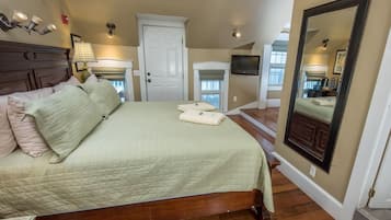 Quarto com cama grande, porta, televisão e espelho.