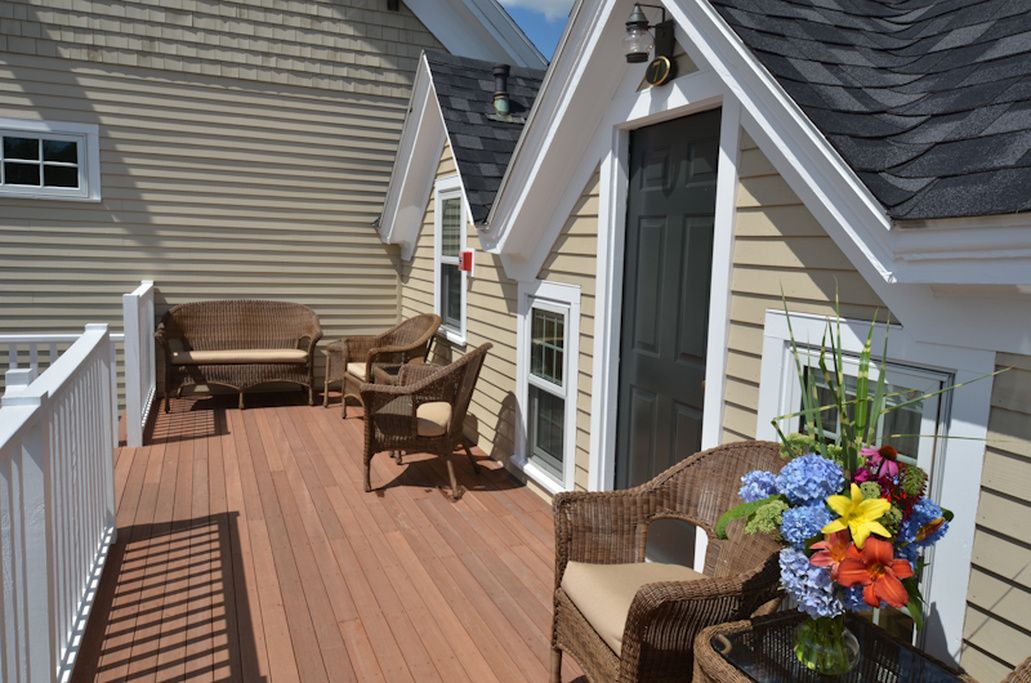 A wooden deck with wicker furniture and a flower arrangement.