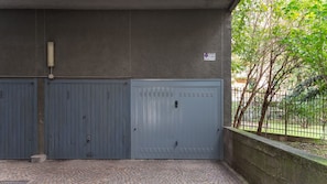 A gated entrance with a metal door, a concrete wall, and a paved area with a brick pattern. - [Free Parking] Elegant 100sqm Apartment (Milano)