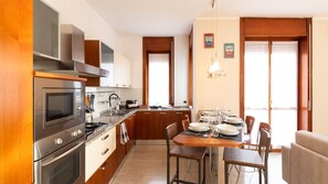 Een moderne keuken met roestvrijstalen apparatuur, houten keukenkastjes en een eethoek met een tafel voor vier personen.