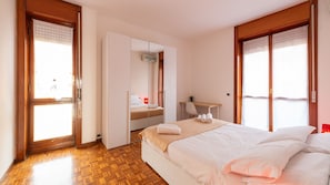 Habitación de hotel con cama, escritorio, armario y vistas a través de la puerta.