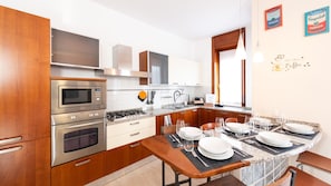 Una cocina moderna con electrodomésticos de acero inoxidable, armarios de madera y un comedor para cuatro.