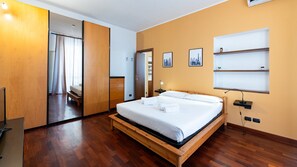Une chambre d’hôtel avec un lit en bois, une armoire, un miroir et une table de chevet.