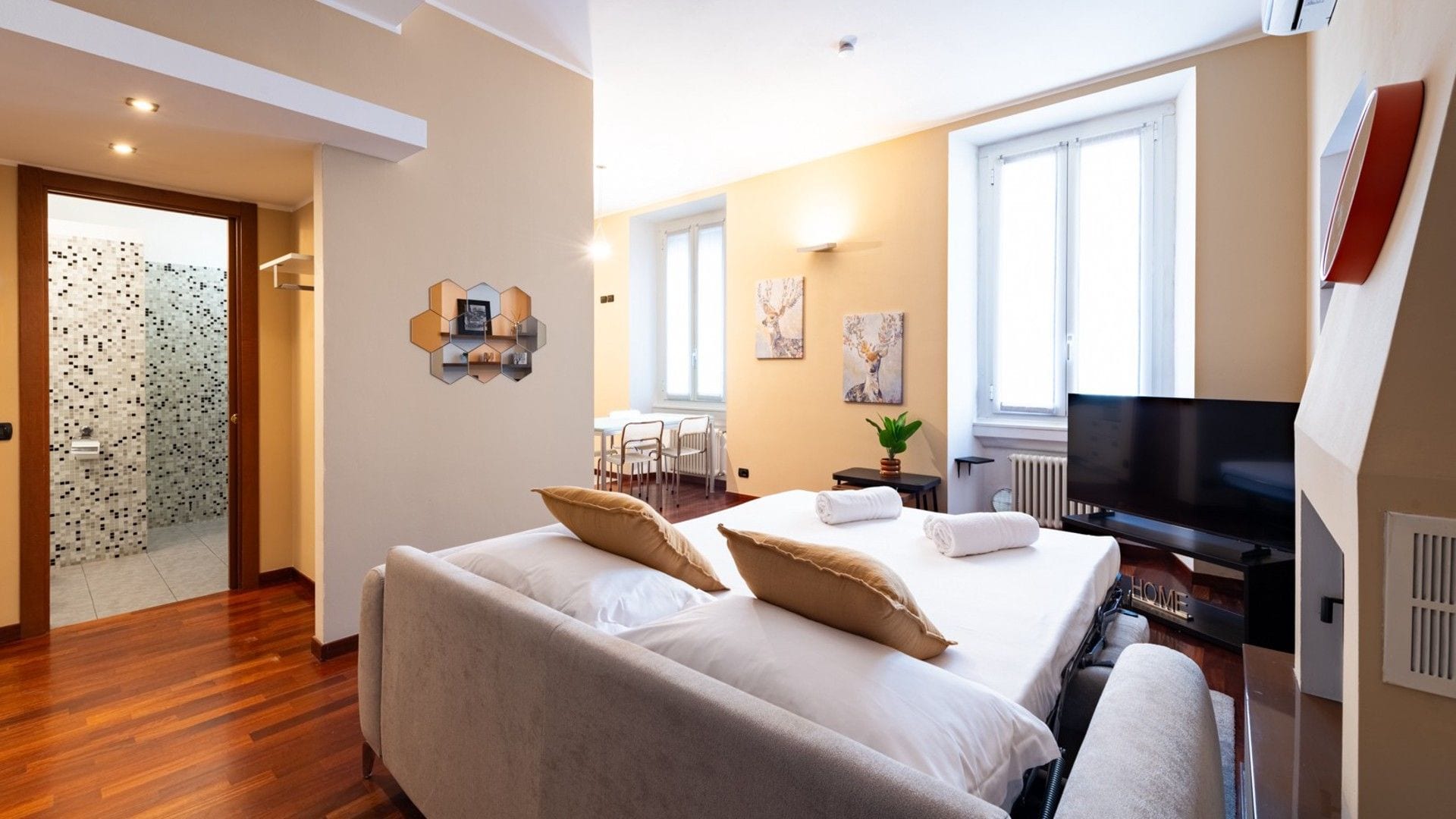 A hotel room with a bed, a TV, and a seating area with a table and chairs.