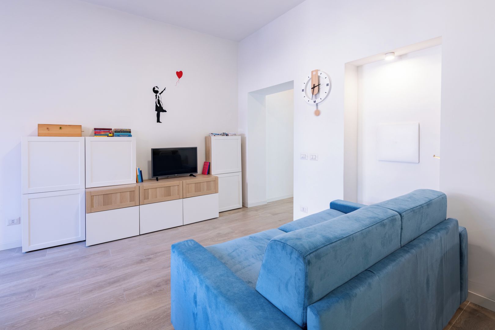 Ein modernes Wohnzimmer mit einem blauen Sofa, einem Fernseher und einem Bücherregal.