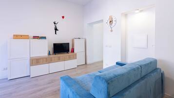 Ein modernes Wohnzimmer mit einem blauen Sofa, einem Fernseher und einem Bücherregal.