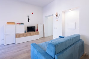 En moderne stue med en blå sofa, et fjernsyn og en bogreol.