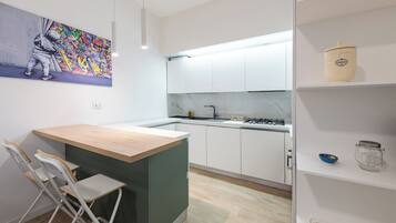 A modern kitchen with white cabinets, a wooden island, and a colorful graffiti artwork on the wall.