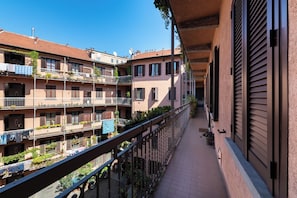 A residential building with multiple balconies, each with plants and laundry hanging. - [Metro M1] Quiet & Modern Apt near Center (Milano)
