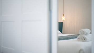 Ein Hotelzimmer mit einem Bett, einer Hängelampe und aufgerollten Handtüchern.