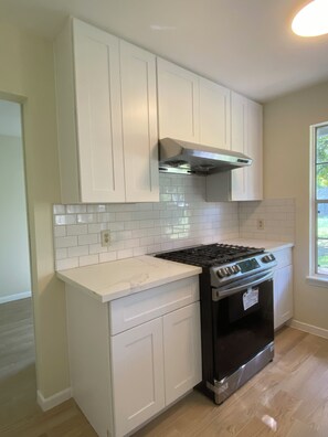 A kitchen with white cabinets, a stainless steel stove, and a tiled backsplash. - Delightful 3-bedroom house in vibrant Central Austin. (Austin)