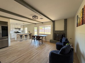 A spacious living area with a fireplace, a dining table with chairs, and a kitchen in the background. - Delightful 3-bedroom house in vibrant Central Austin. (Austin)