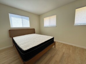A bedroom with a bed, two windows, and wooden flooring. - Delightful 3-bedroom house in vibrant Central Austin. (Austin)