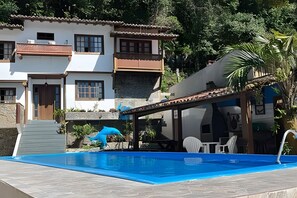 Ein Poolbereich mit einem klaren, blauen Pool, einer kleinen Statue und einem Gebäude mit einem Ziegeldach.