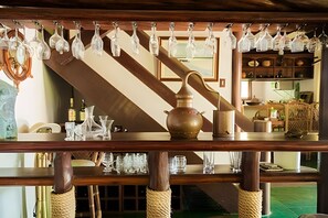 A wooden bar with hanging glassware and a brass pot. - Casa 2 Porto Seguro 4 Quartos 2 Piscina (Porto Seguro)