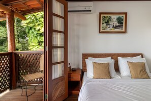 A bedroom with a wooden bed, white linens, a wooden nightstand, and a framed picture on the wall. - Casa 2 Porto Seguro 4 Quartos 2 Piscina (Porto Seguro)