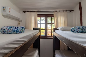 Ein Zimmer mit zwei Etagenbetten, einem fensterbelaubten Fenster und einer Wand-Klimaanlage.
