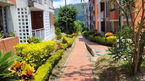 Un chemin bordé d’immeubles à plusieurs étages dotés de balcons, entouré d’une végétation bien entretenue et surplombé d’un ciel dégagé.
