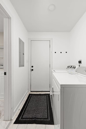 A laundry room with a white door, a washing machine, and a dryer. - 2-bedroom house in peaceful Indianapolis with cozy vibes (Indianapolis)