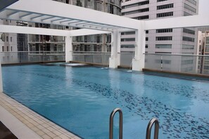 En indendørs swimmingpool med krystalklart vand, omgivet af en hvid konstruktion med glaspaneler.