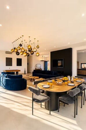 A modern dining area with a round table, chairs, and a unique chandelier.