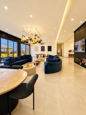 A modern living room with a large sofa, a coffee table, and a dining area with a round table and chairs. - Luxury Villa with Padel Court, Pool, and Jacuzzi in Marrakech (Marrakech)