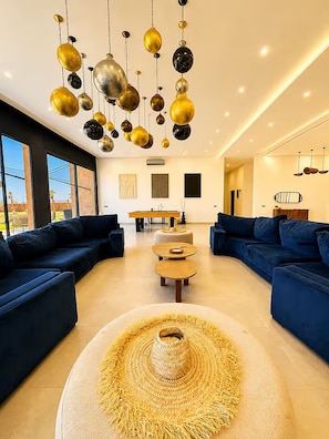 A modern living room with two sofas, a coffee table, and a hanging light fixture. - Luxury Villa with Padel Court, Pool, and Jacuzzi in Marrakech (Marrakech)