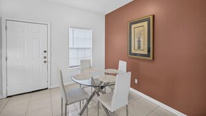 A dining area with a white door, a window with blinds, a framed picture on the wall, and a table with chairs. - Terracotta Central Spacious 2Bed/2bath Comfy Calm (McAllen)