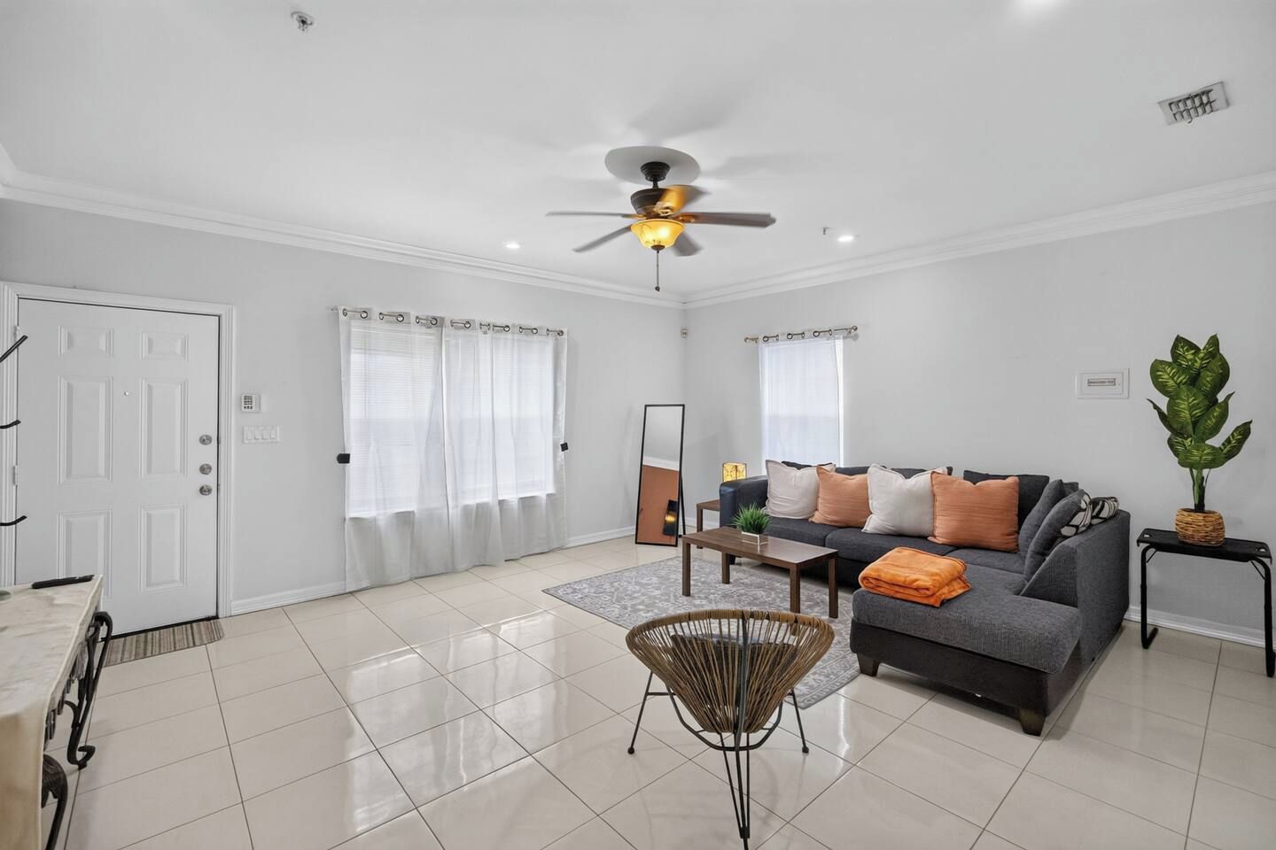 A modern living room with a grey sofa, a coffee table, a floor lamp, and a ceiling fan.