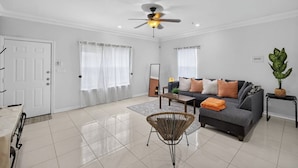 A modern living room with a grey sofa, a coffee table, a floor lamp, and a ceiling fan. - Terracotta Central Spacious 2Bed/2bath Comfy Calm (McAllen)