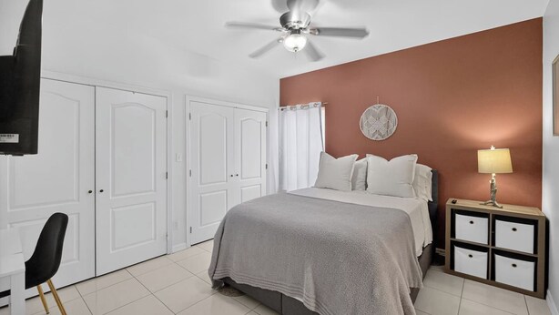 A bedroom with a bed, a nightstand, a lamp, a ceiling fan, and white doors. - Terracotta Central Spacious 2Bed/2bath Comfy Calm (McAllen)