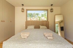 A bedroom with a large bed, a window with a view of greenery, and a wardrobe. - Villa d’architecte avec piscine - Entre Marseille, Cassis & les Calanques (Aubagne)