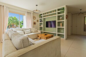A living room with a sofa, coffee table, TV, and shelves with decorative items. - Villa d’architecte avec piscine - Entre Marseille, Cassis & les Calanques (Aubagne)