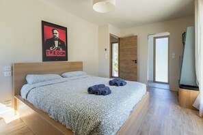 Ein Schlafzimmer mit einem großen Bett, einem Poster an der Wand und einer Tür zu einem anderen Raum.