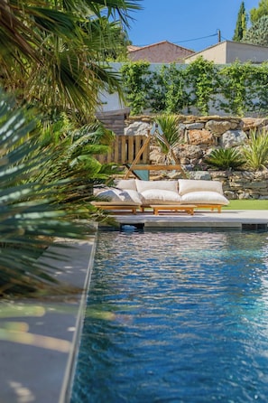 Ein Schwimmbecken mit Holzterrasse und Liegestühlen.