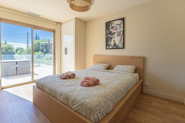 Ein Schlafzimmer mit einem Bett, einem großen Fenster und einem Gemälde an der Wand.