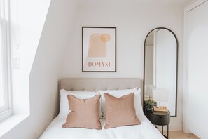 A bedroom with a bed, pillows, a framed artwork, a mirror, and a bedside table. - Stylish 1-bed Apt in Clapham - 1 Minute from tube (London)