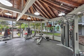 Ein Fitnessraum mit Trainingsgeräten, großen Fenstern und einer überdachten Decke.