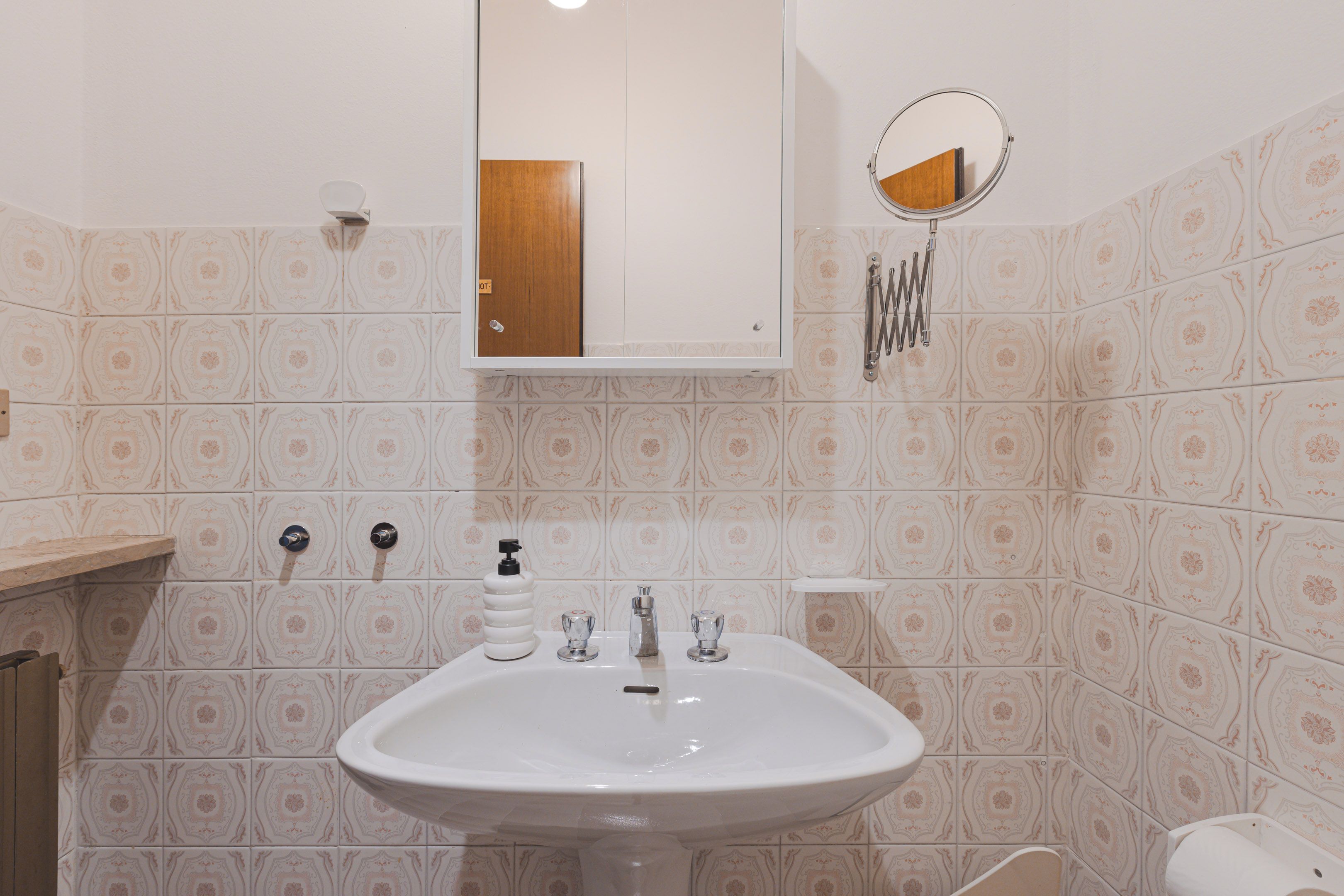 A bathroom with a white sink, a mirror, a towel rack, and a toilet.