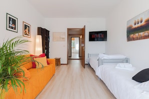 Una camera d'albergo con un divano, un letto, una TV e una libreria.