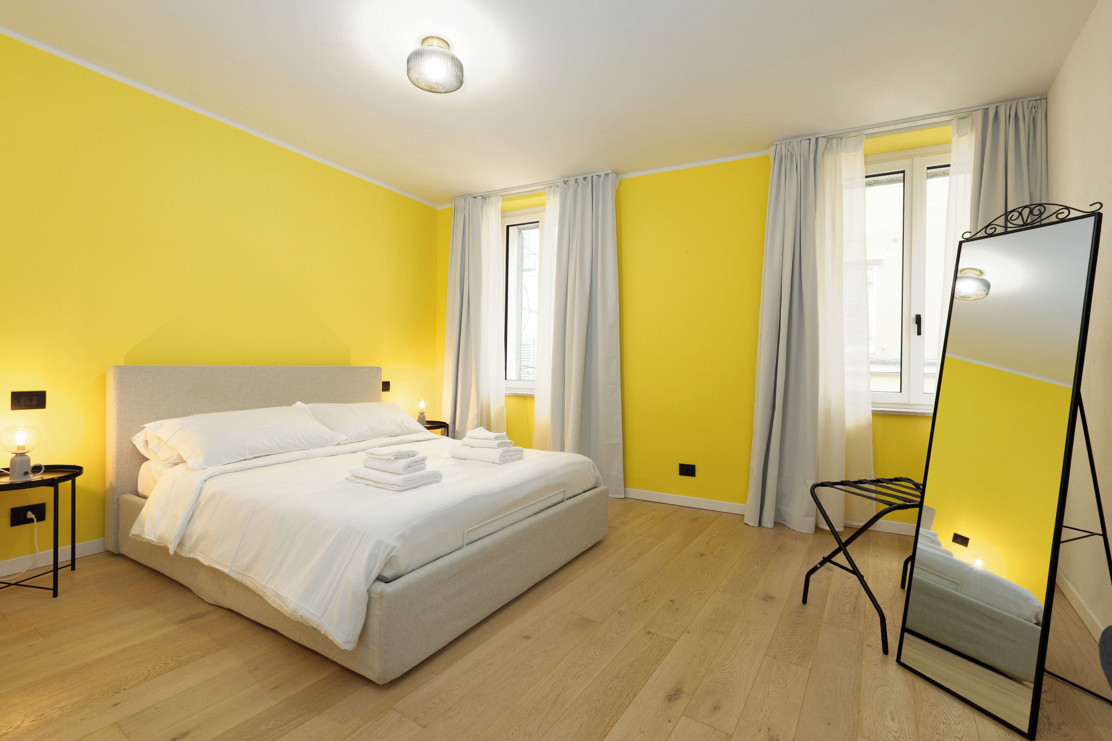 Une chambre d’hôtel avec un lit, une table de chevet, une lampe et un miroir.