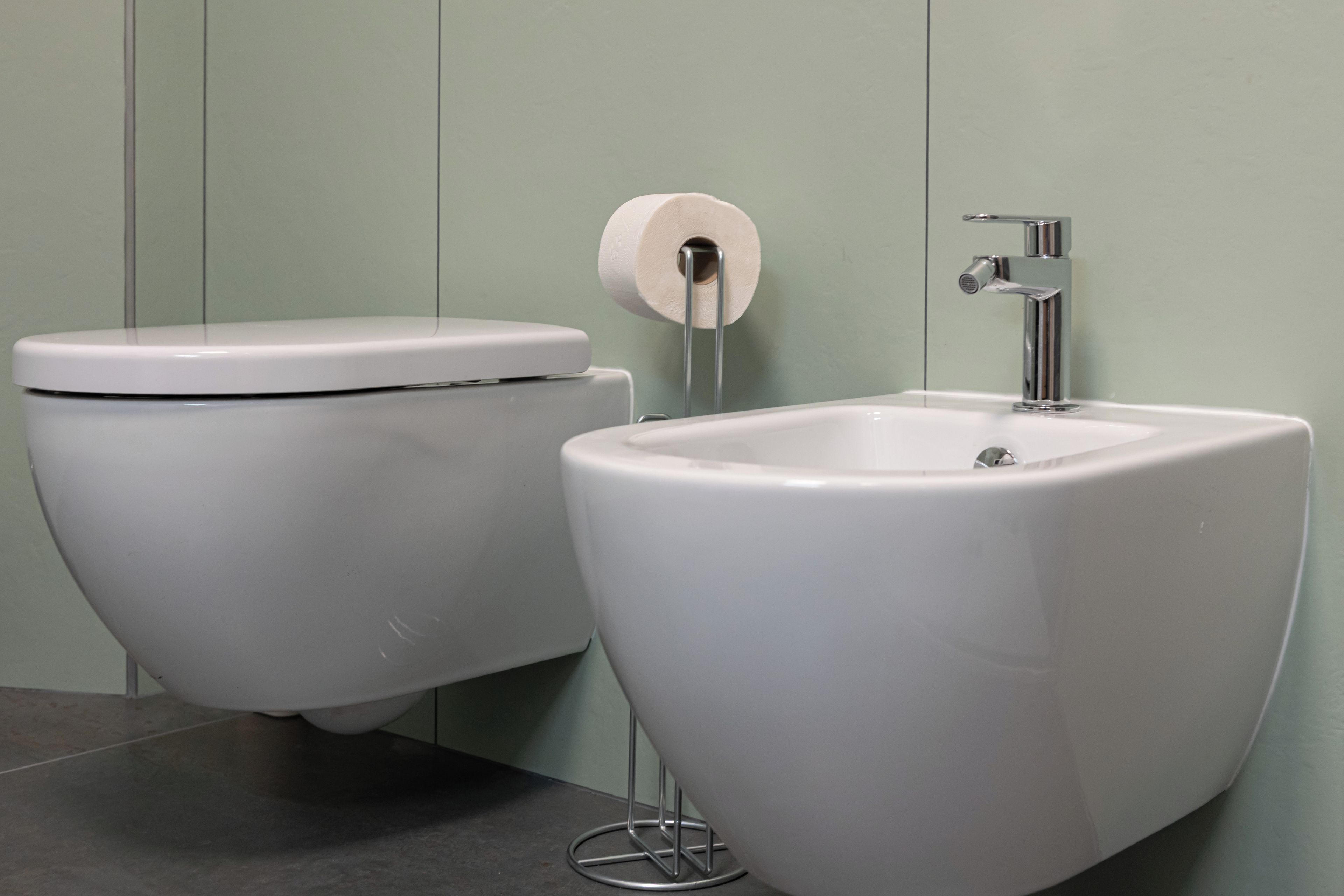 A modern bathroom with a toilet and a pedestal sink.