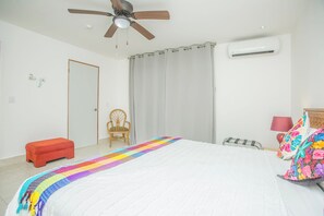 A bedroom with a bed, a chair, an air conditioning unit, and a ceiling fan. - Jaguar Condos Cozumel The Private Group Villa / Casa 1-24 w/2 pools Downtown (Cozumel)